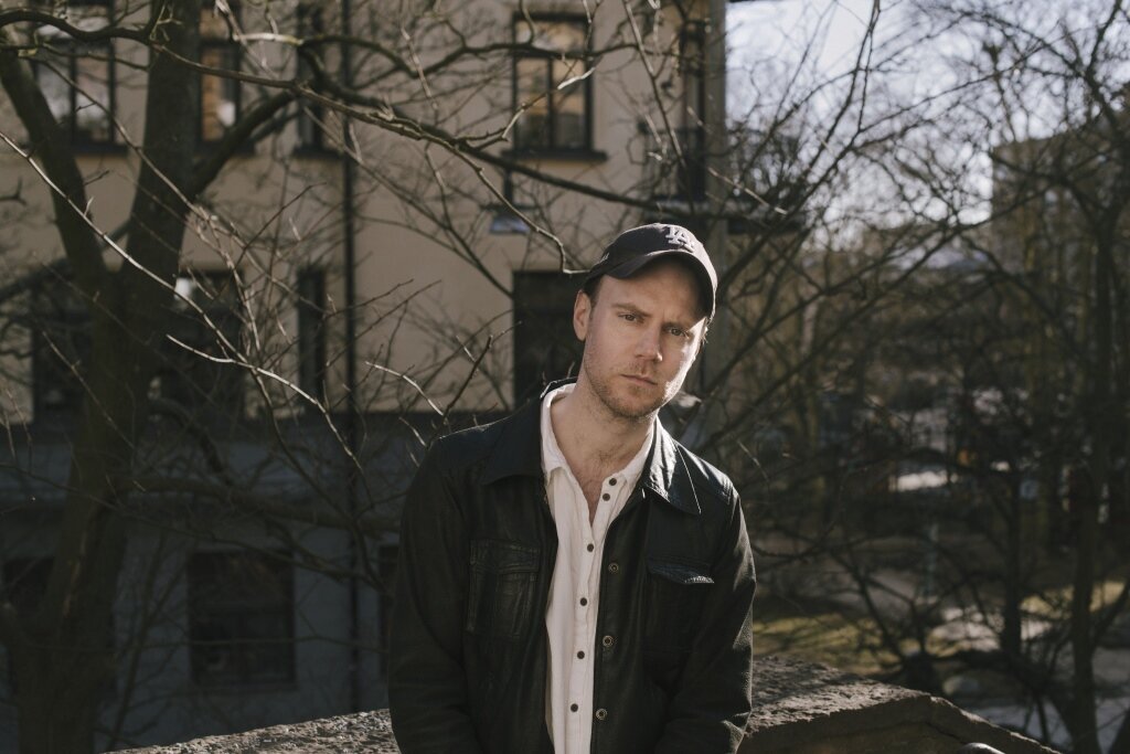 Bildet viser Tom Malmquist som står i en bakgård.