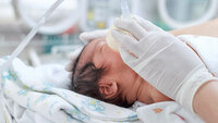 Syk baby Liten baby som får oksygen tilført gjennom maske