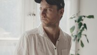 Bildet viser Tom Malmquist som ser ut av et vindu.